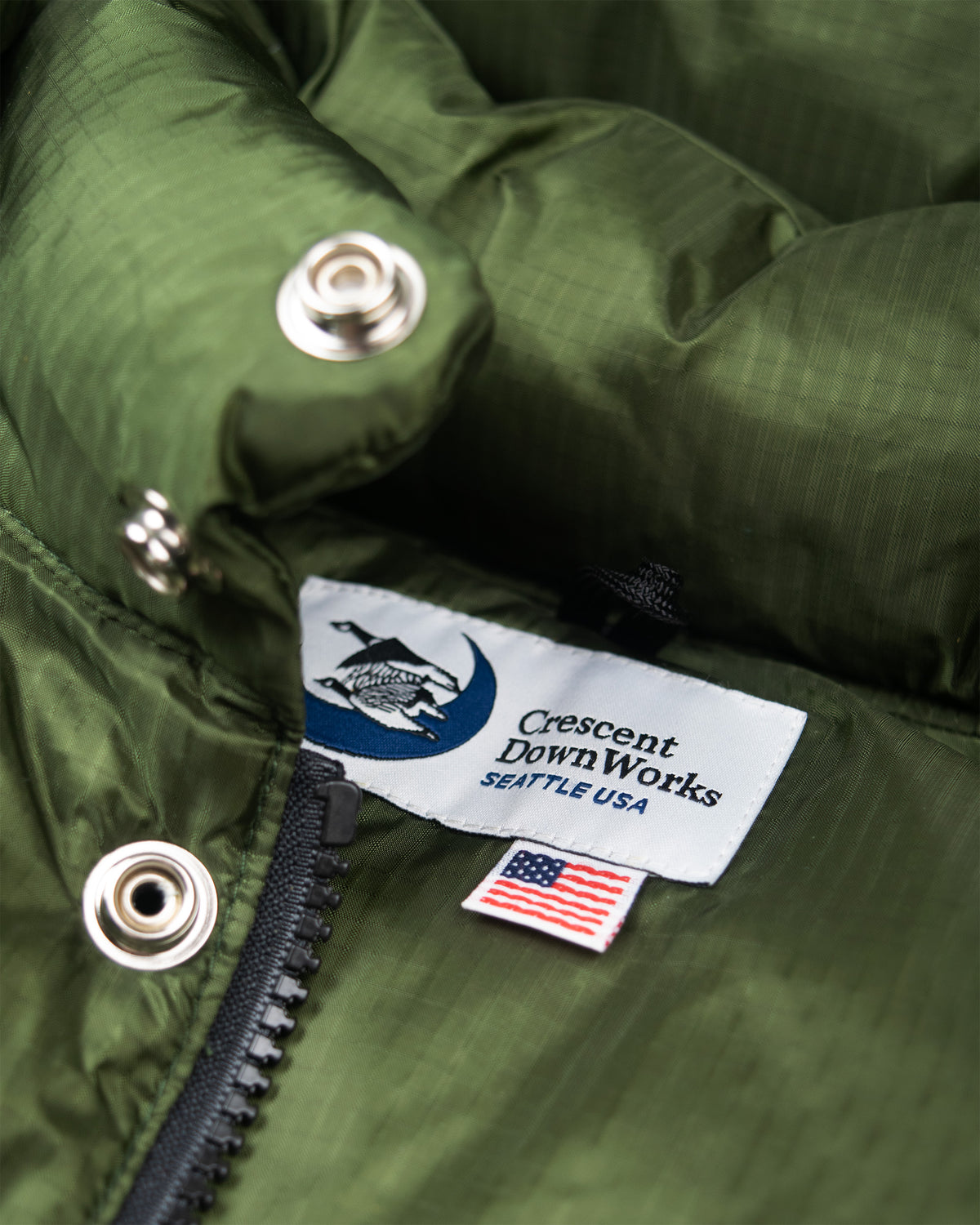 Olive green crescent downworks down sweater puffer jacket with ripstop nylon and silver snap buttons