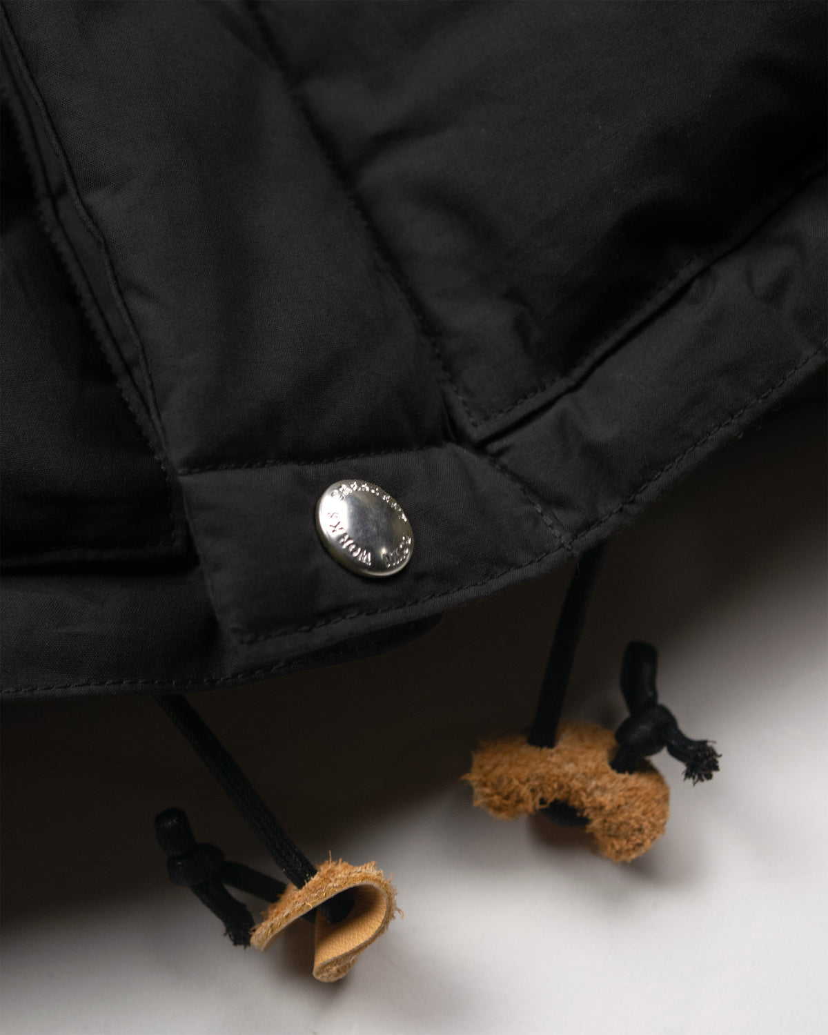 Black down sweater puffer jacket with silver button and leather toggles made from dry wax cotton
