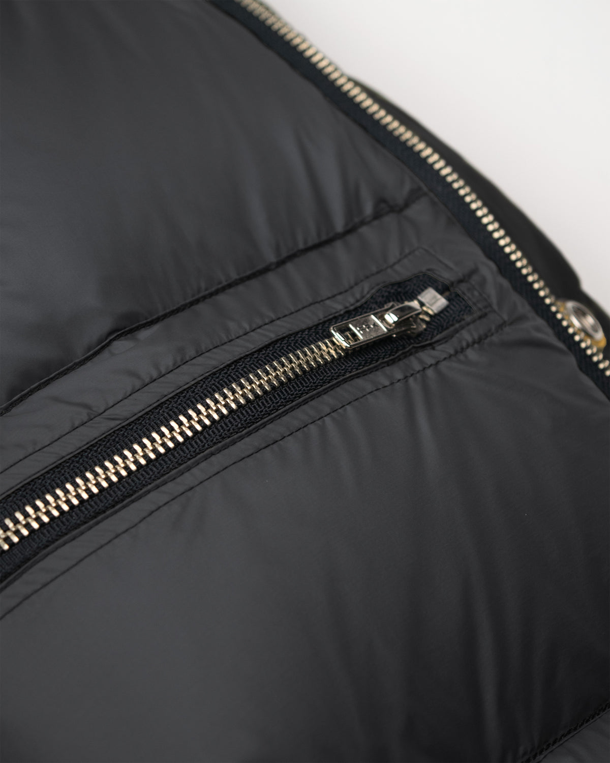 Black down sweater in dry wax cotton with a sleek quilted puffer design and metallic zipper accents