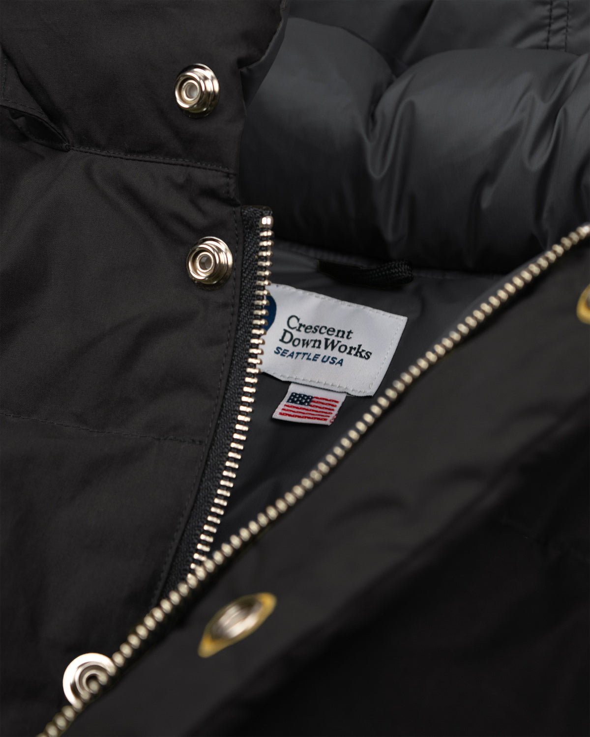 Black down sweater jacket in dry wax cotton with leather snap reinforcement and zipper hardware