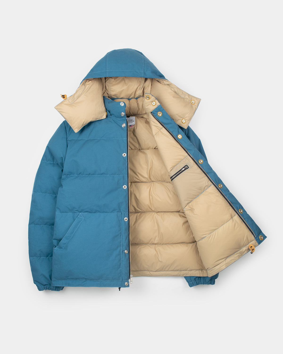 Down sweater dry wax cotton blue puffer jacket with beige interior hood and silver buttons along front zipper