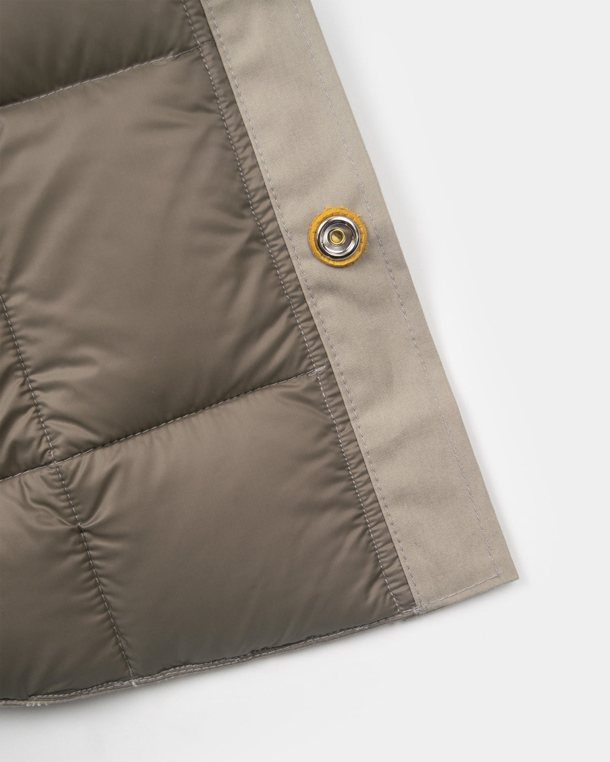 Stone quilted down shirt with metallic snap button and yellow rubberized ring made of dry wax cotton in stone color
