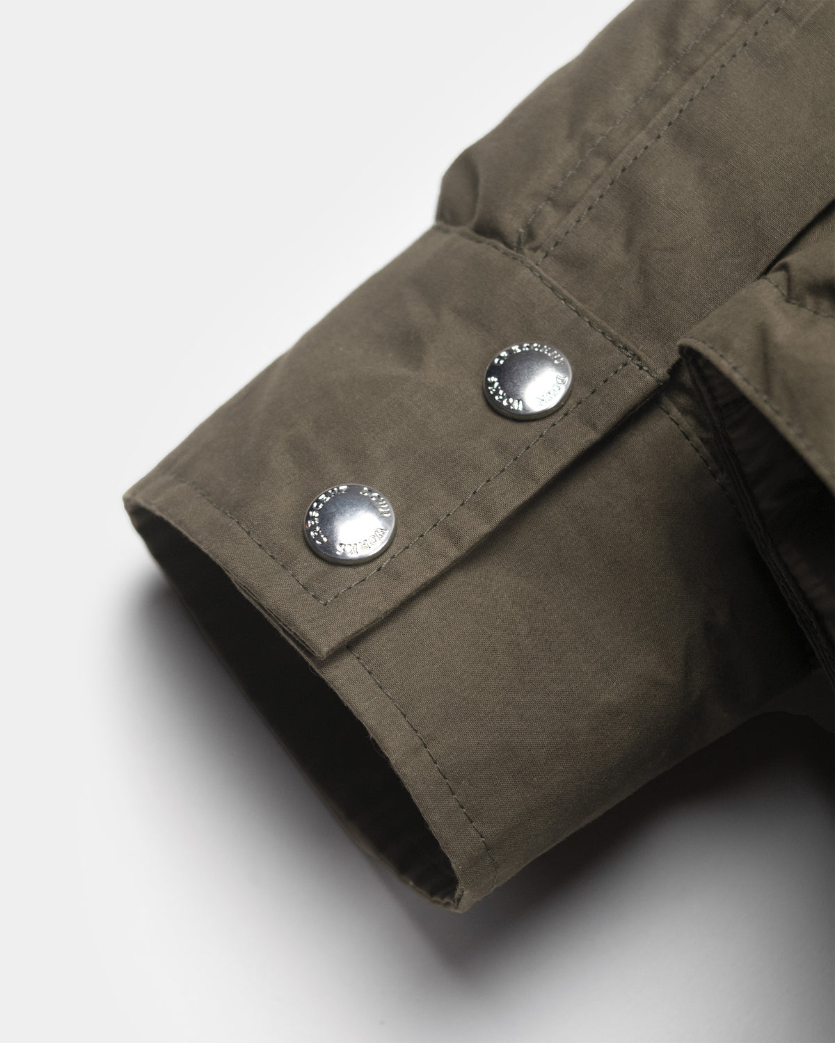 Olive green down shirt sleeve in dry wax cotton canvas with two silver toned metal buttons and tent finish
