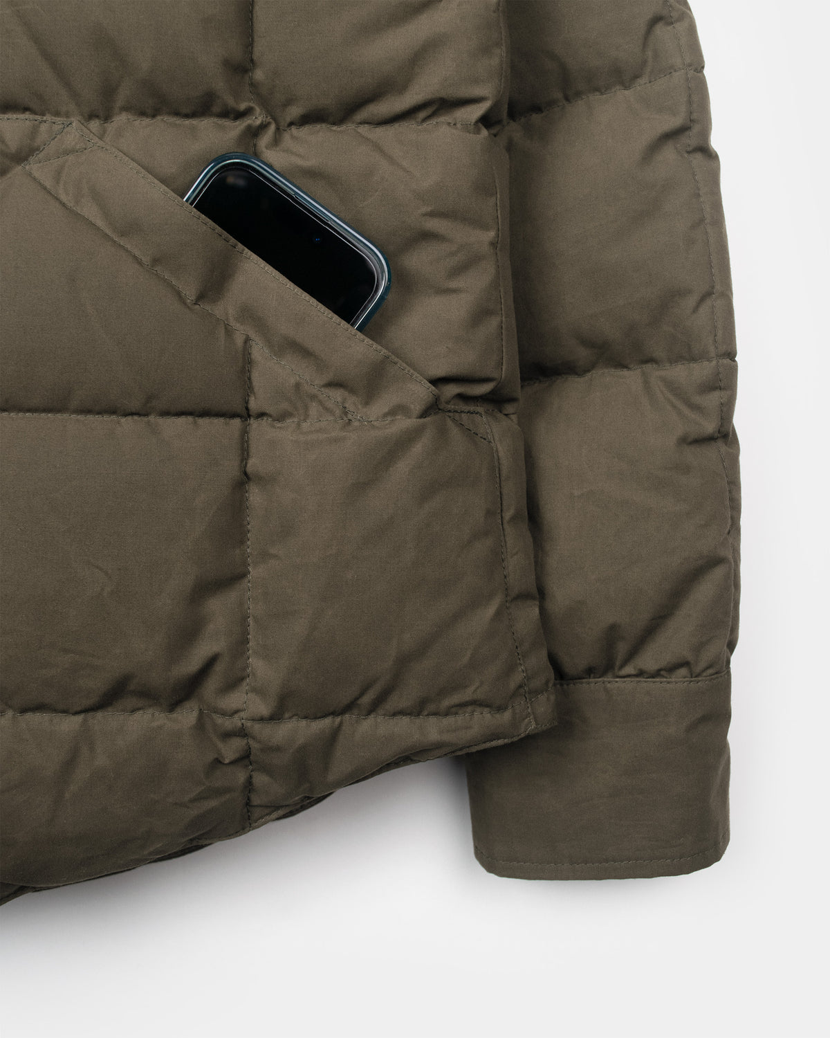 Olive green quilted puffer down shirt with dry wax cotton and a phone visible in the side pocket