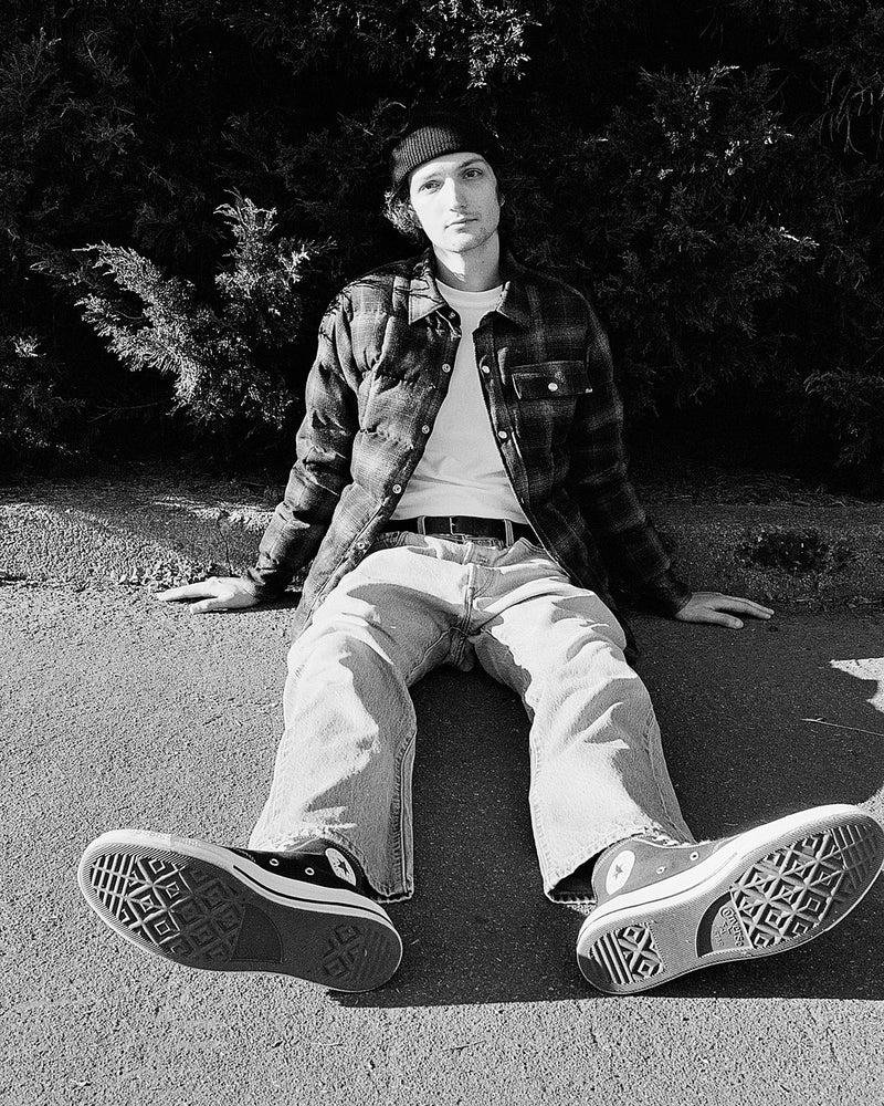 1990 Male Model Sitting on ground wearing Down Shirt in Plaid black and white
