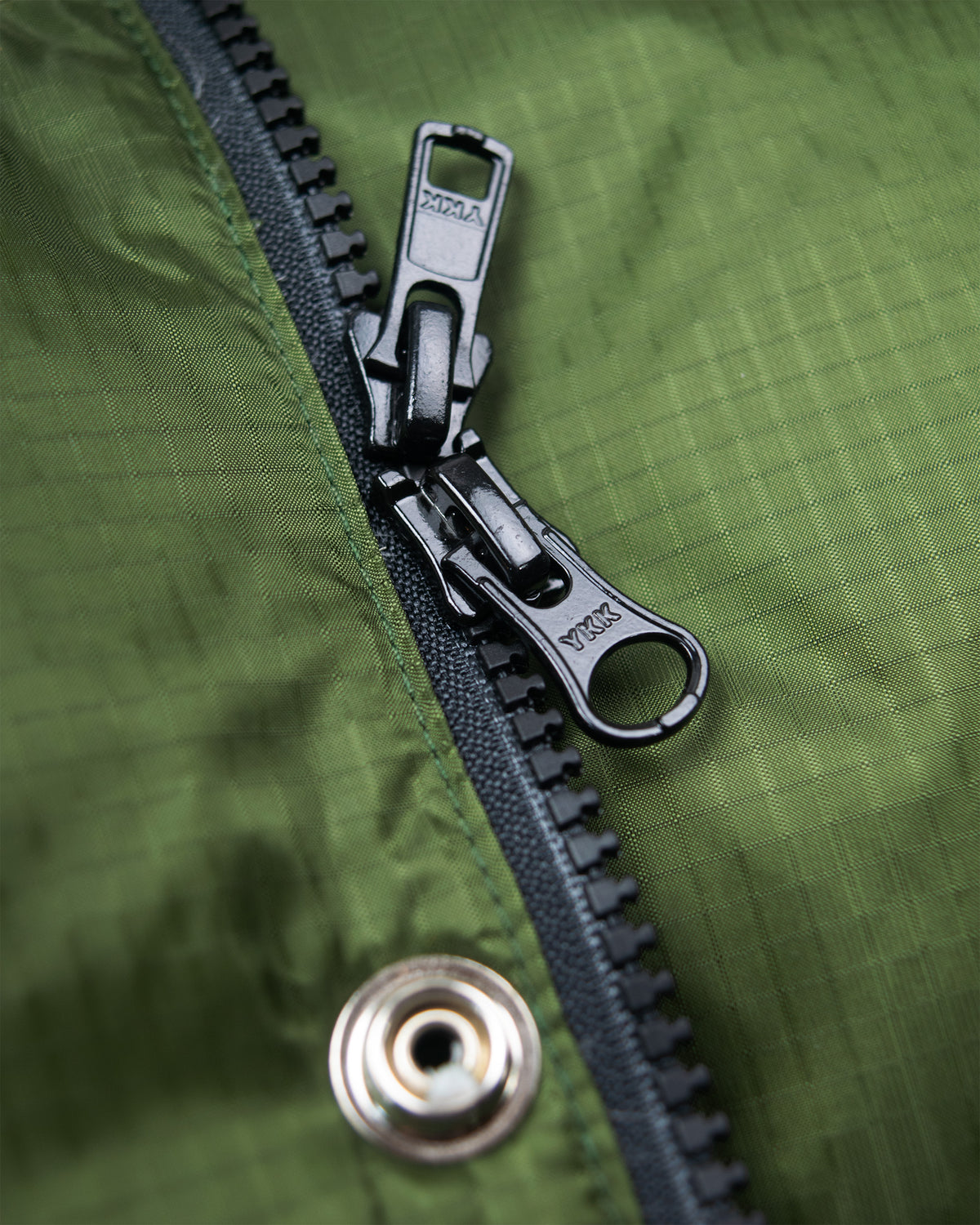 Black ykk zipper with metallic pull tab on down italian vest ripstop nylon in green fabric