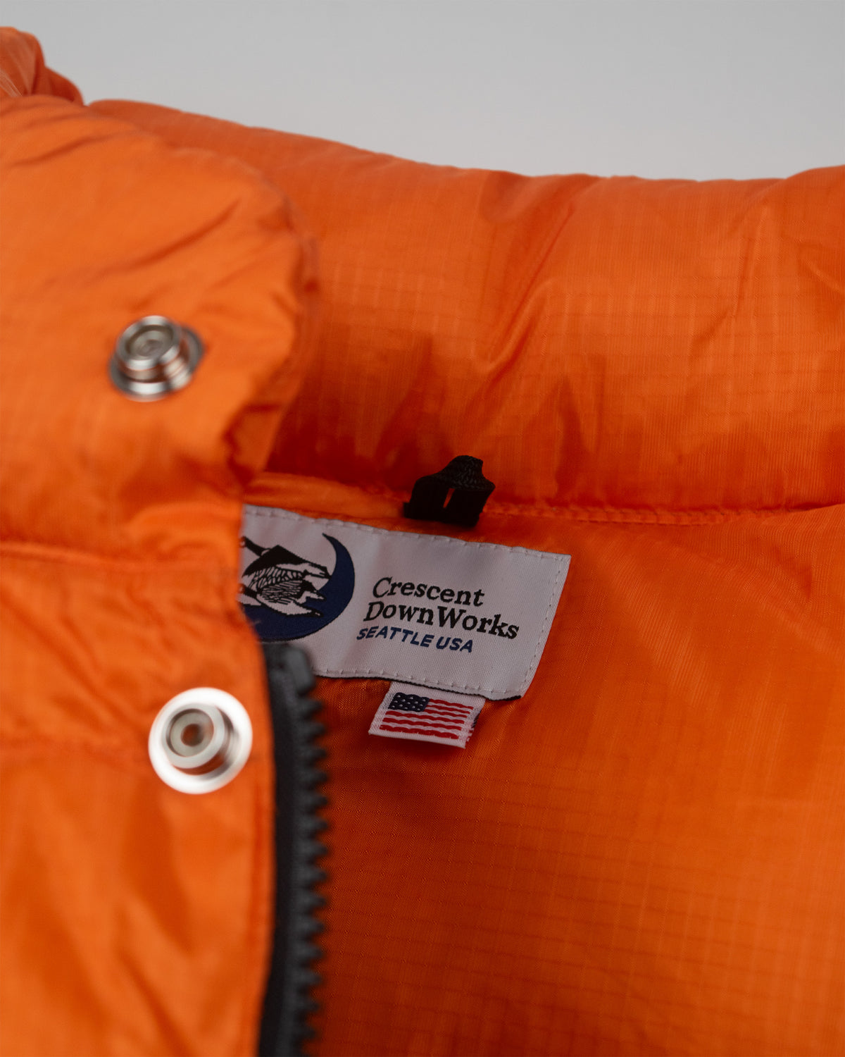 Bright orange down italian puffer vest with quilted ripstop nylon texture and silver snap buttons
