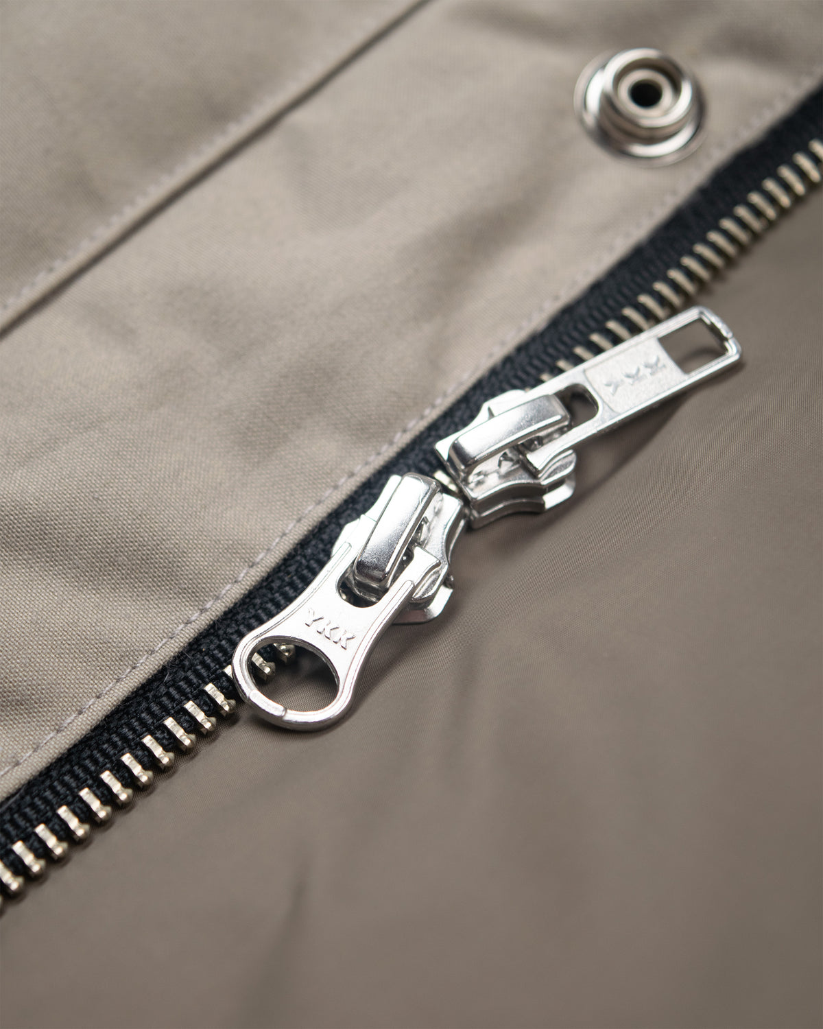 Silver metal zipper on dry wax cotton fabric of down italian vest stone color