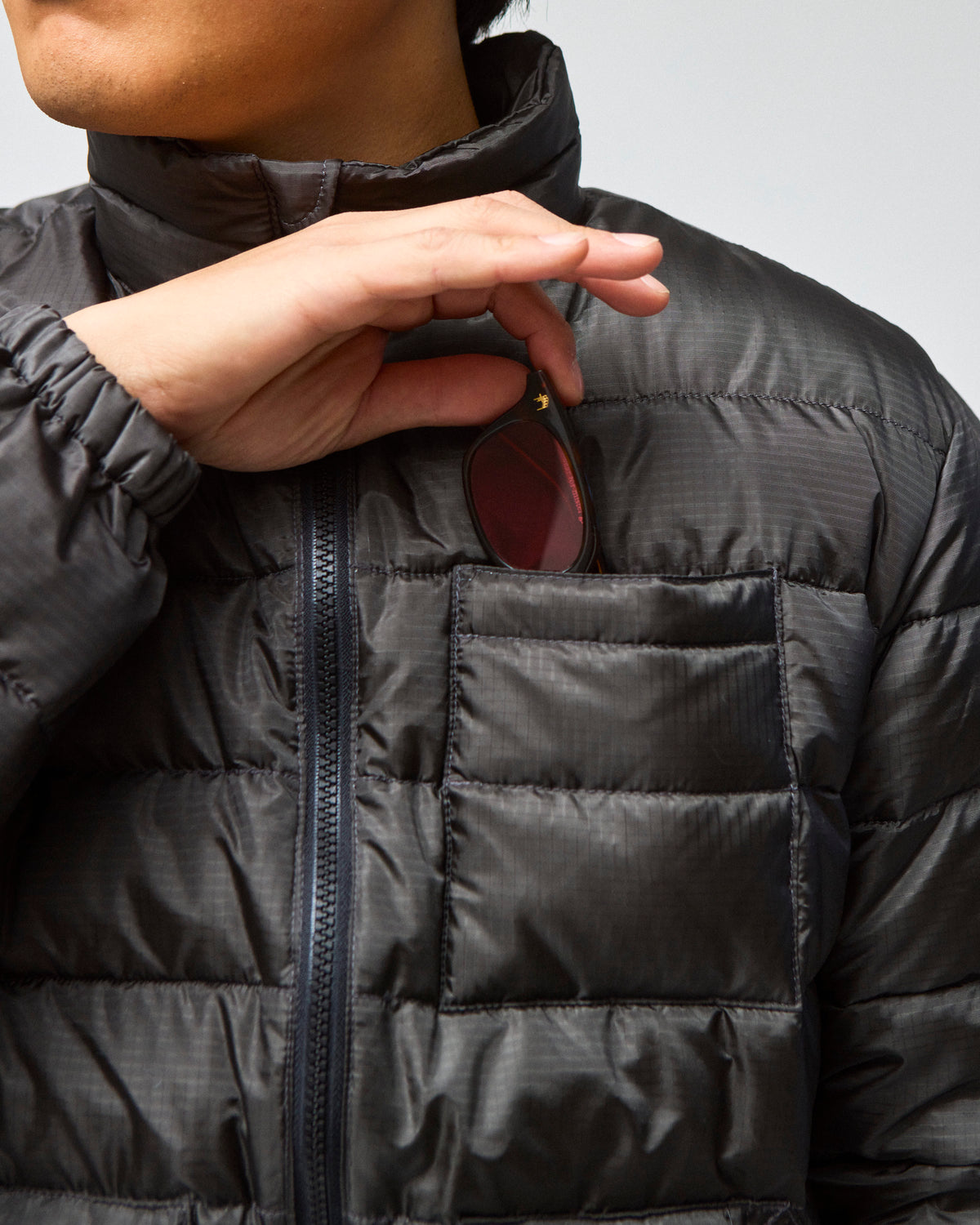 Closeup view of model wearing a Seattle Jacket in Charcoal, hand showing off the chest pocket