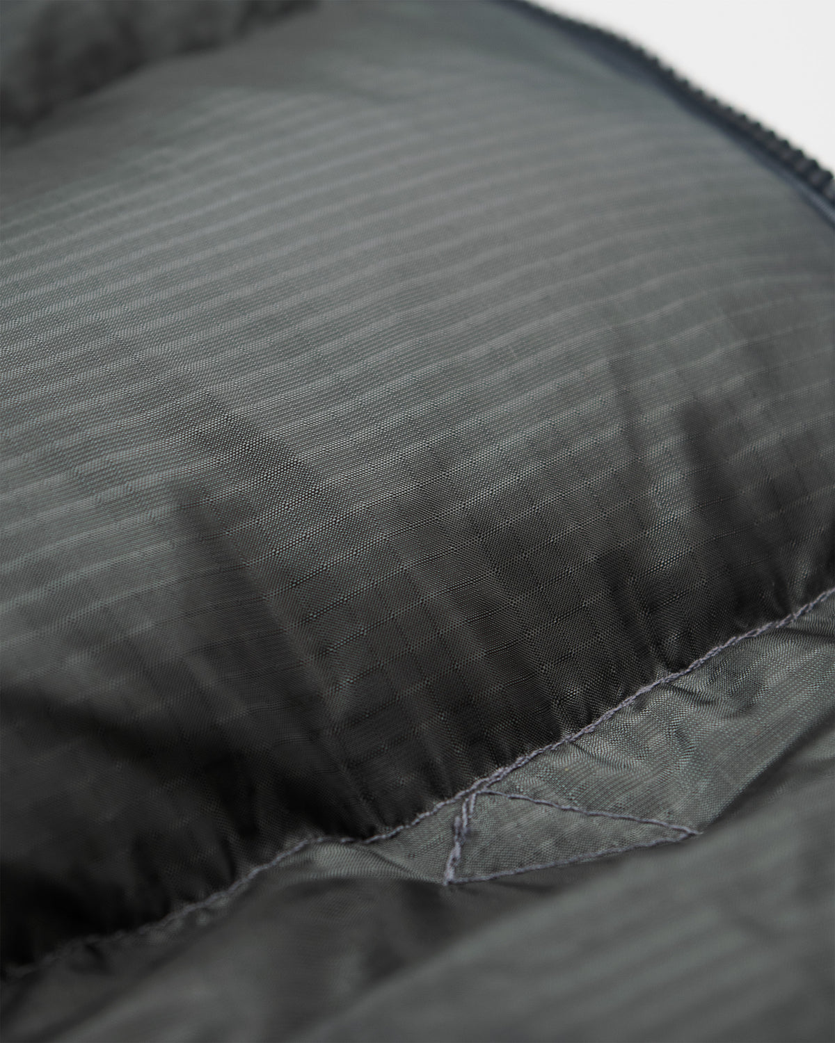 Charcoal quilted vest with subtle vertical ribbing and reinforced stitching made of ripstop nylon