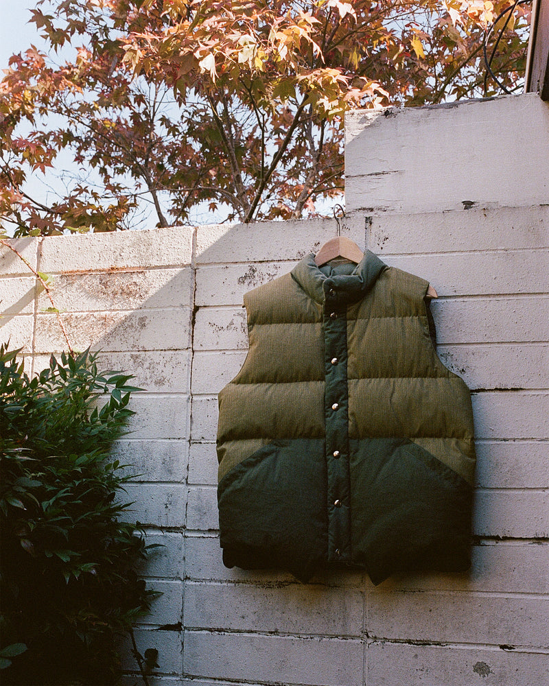 2010 Outdoor photo of NxNW Vest in Army Cotton hanging on cement wall in garden