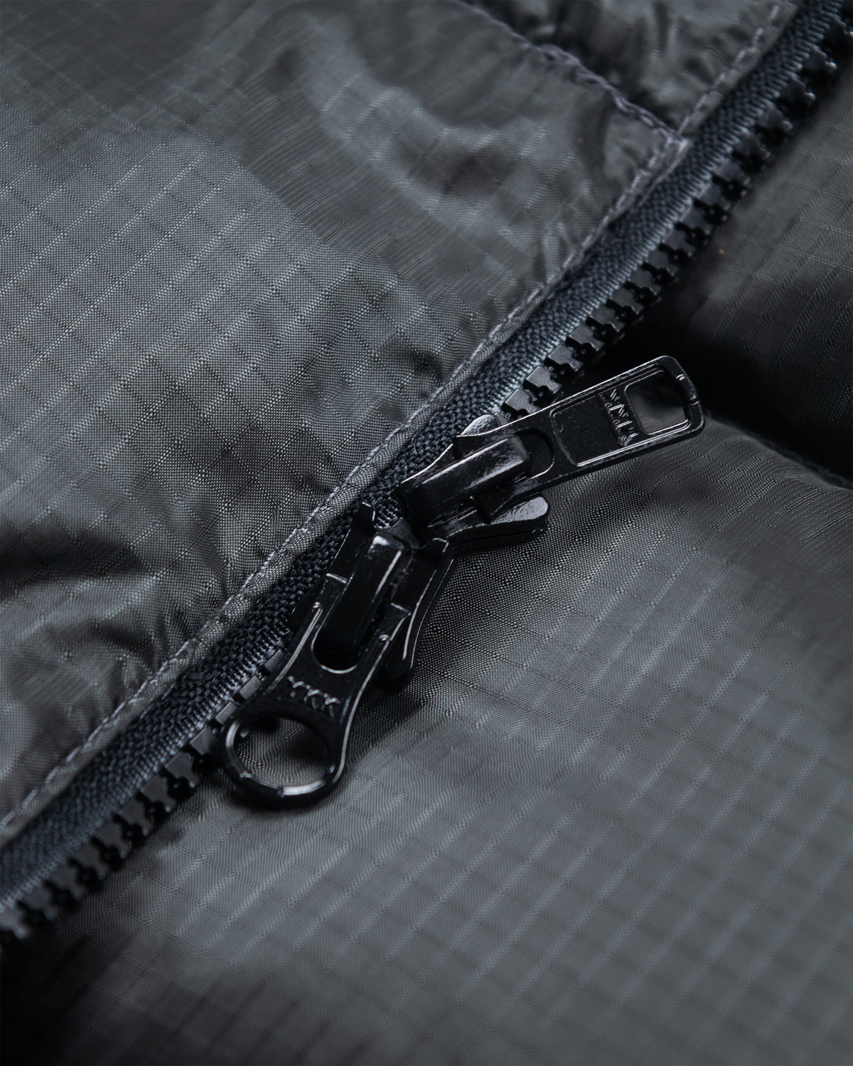 Black metal zipper with matte finish on charcoal ripstop nylon fabric of classico down parka 