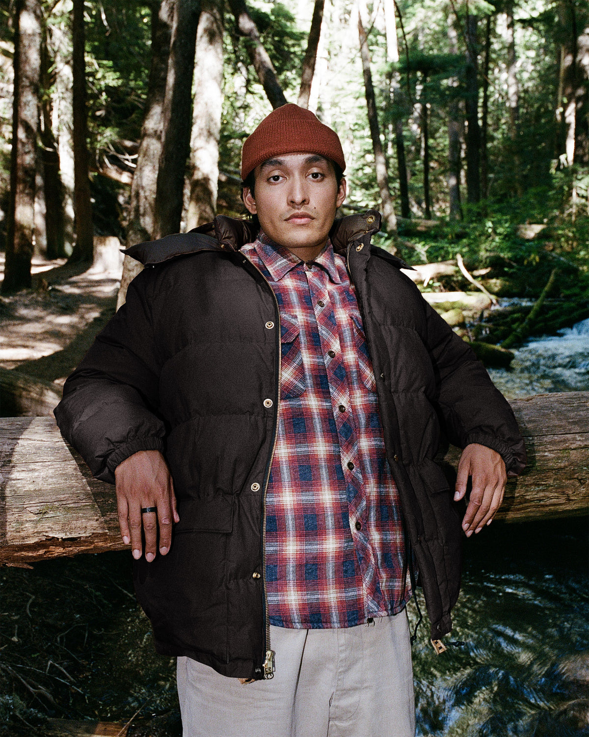 Man wearing classico down parka black made of dry waxed cotton with brown beanie and plaid shirt visible underneath