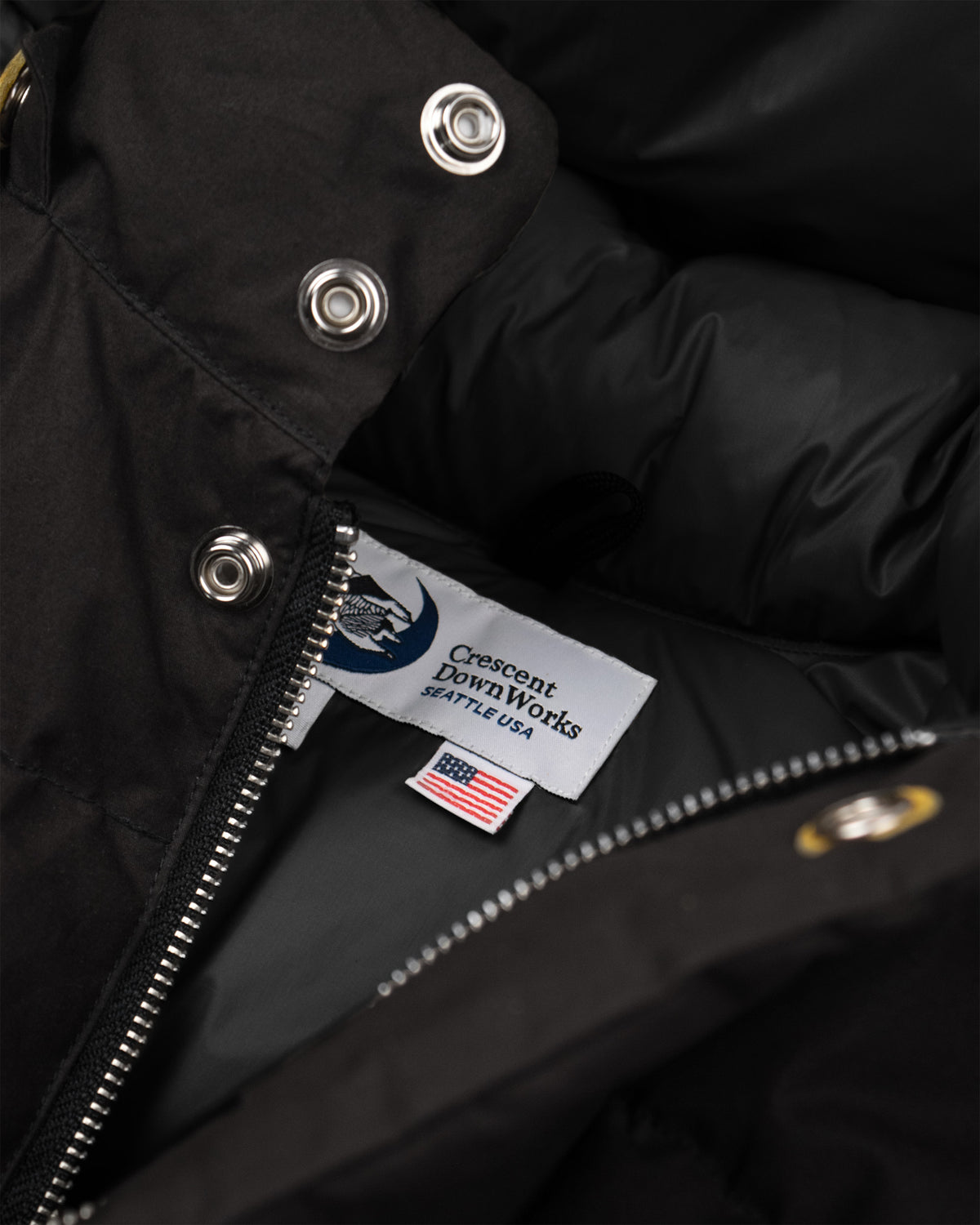 Black classico down parka in dry waxed cotton with silver snap buttons, zipper, and crescent downworks label