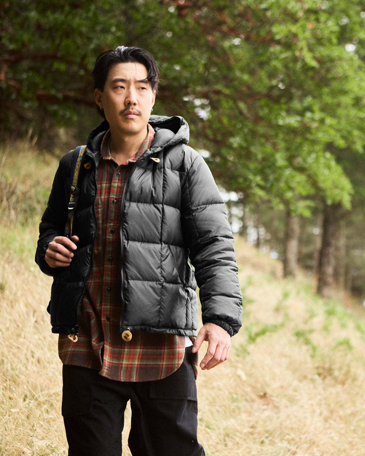 Black quilted puffer jacket with hood and leather snap reinforcement made of ripstop nylon 