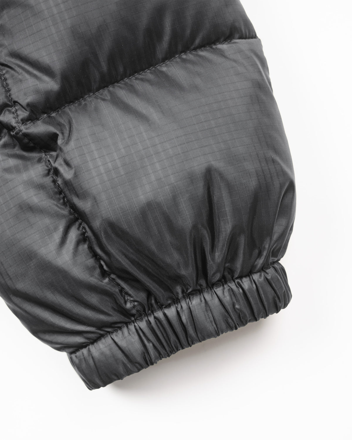 Black hooded sweatshirt sleeve in charcoal ripstop nylon with subtle grid pattern and elasticated cuff