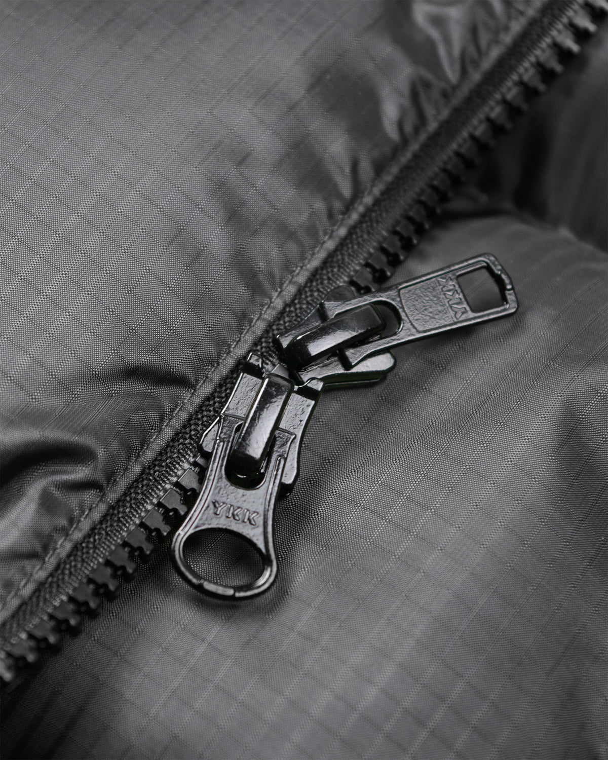 Black metal zipper with textured pull tab on charcoal ripstop nylon hooded sweatshirt