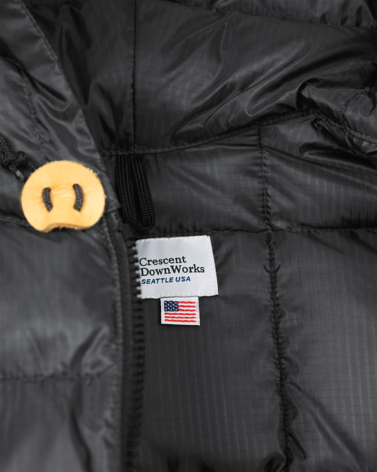 Black puffer jacket with yellow button and crescent downworks label in charcoal hooded ripstop nylon sweatshirt style