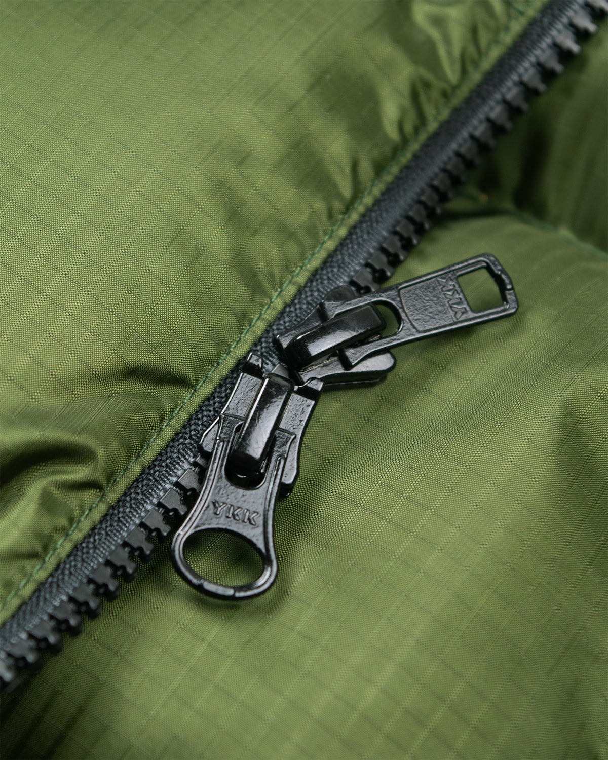 Black metal zipper with sturdy pull tab on olive green ripstop nylon hooded sweatshirt