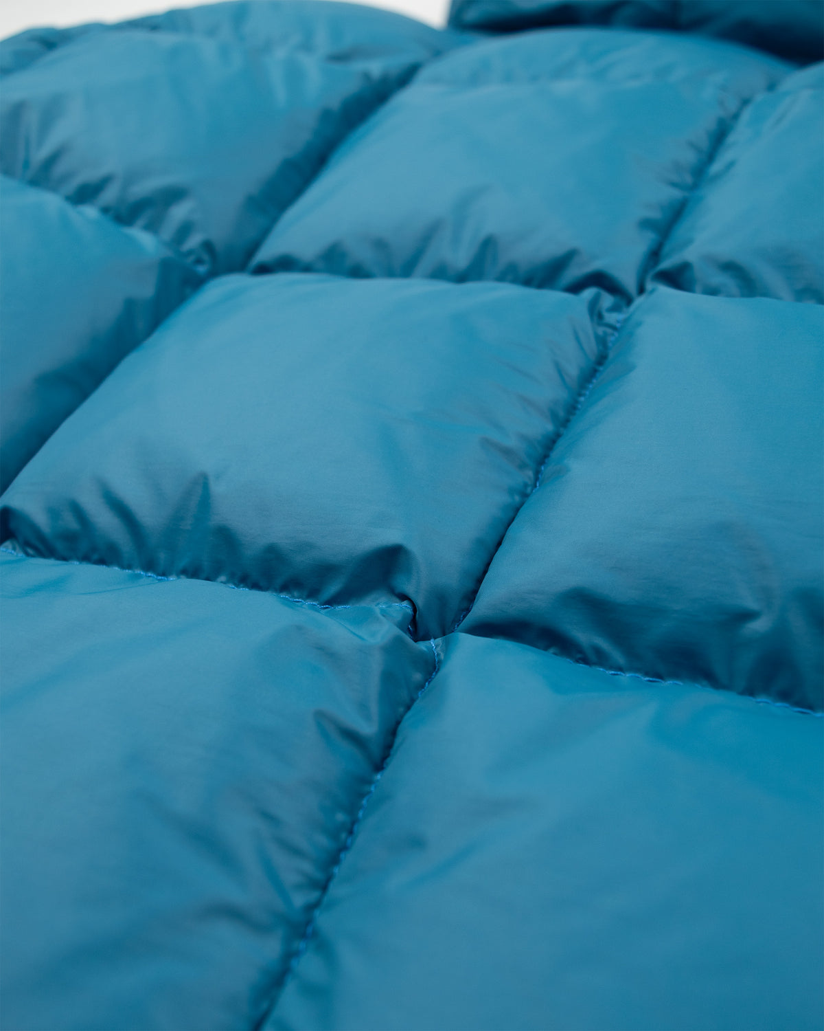 Blue quilted down jacket made of smooth shiny nylon fabric with stitched squares