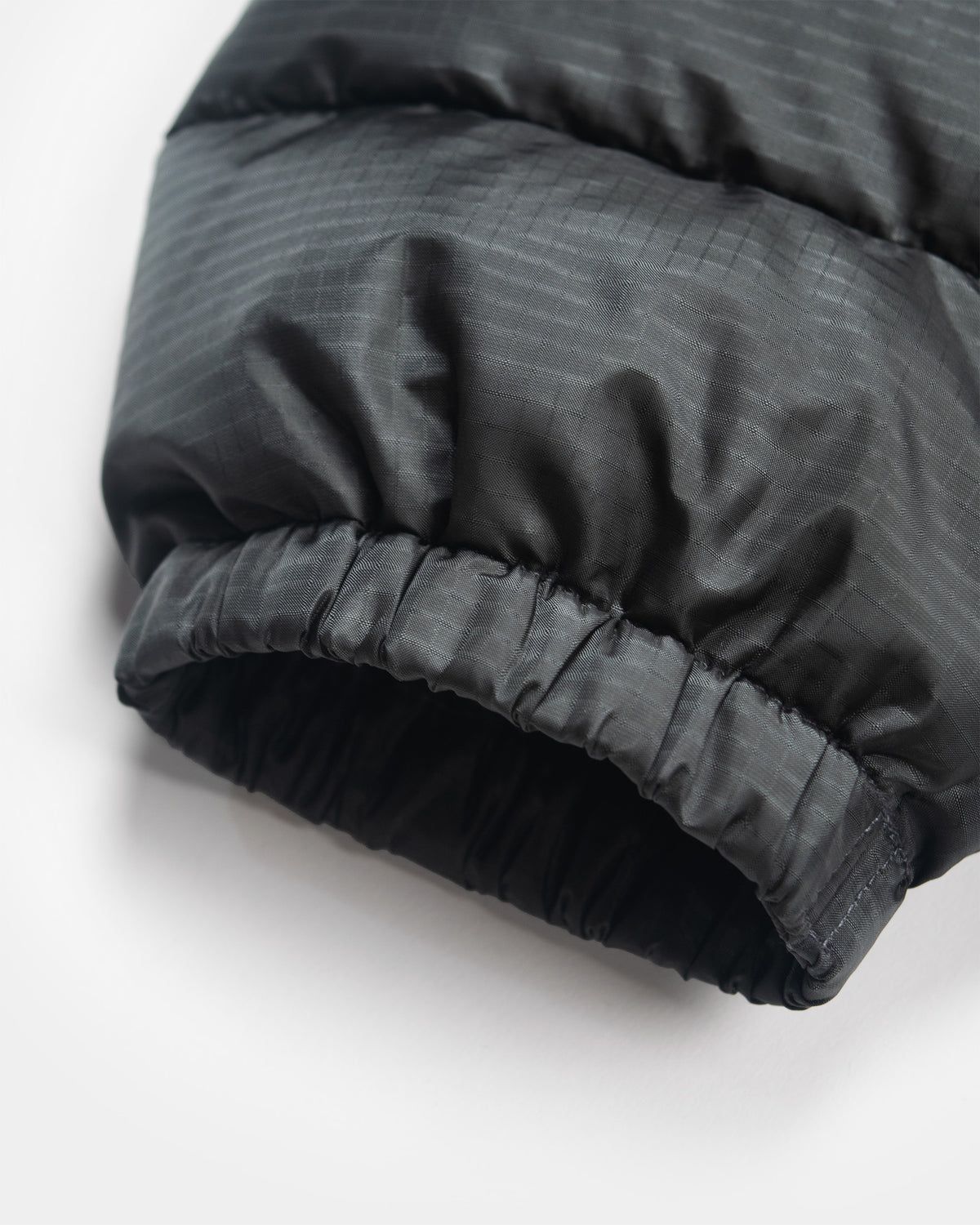 Close-up of a  charcoal Seattle Liner jacket sleeve with horizontal quilting and an elasticized cuff, shown on a white background.