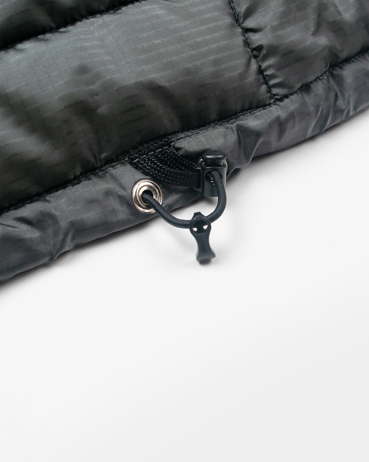 A closeup of a charcoal Seattle Liner jacket showing the pull tab at the hem