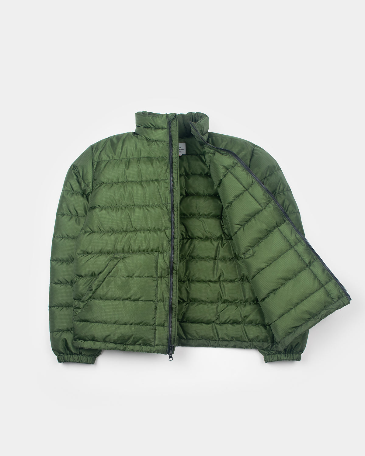 A flat photo a green Seattle Liner jacket with horizontal quilting, against a light gray background.