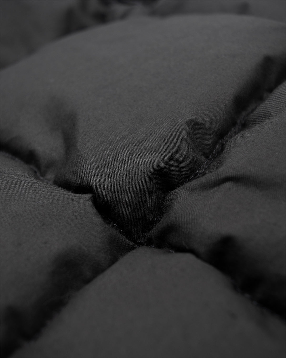 Black quilted fabric with visible stitching and puffy texture on the down tote dry wax cotton 