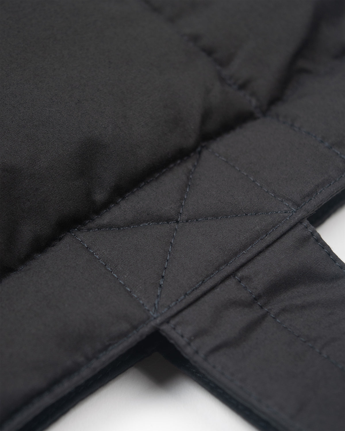 Black down tote made of dry wax cotton featuring quilted fabric with precise diagonal diamond stitching