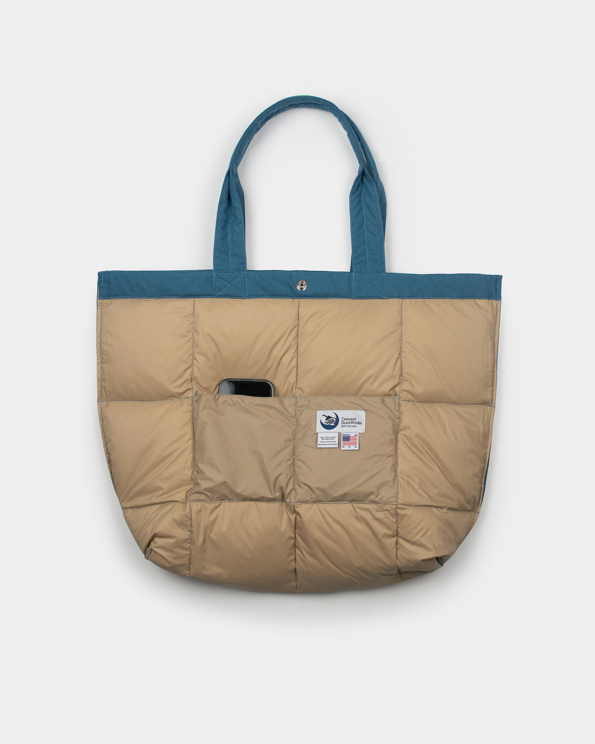 A quilted puffer tote bag turned inside out with a contrasting Robin blue top trim and handles, featuring an inside pocket with a small patch logo.